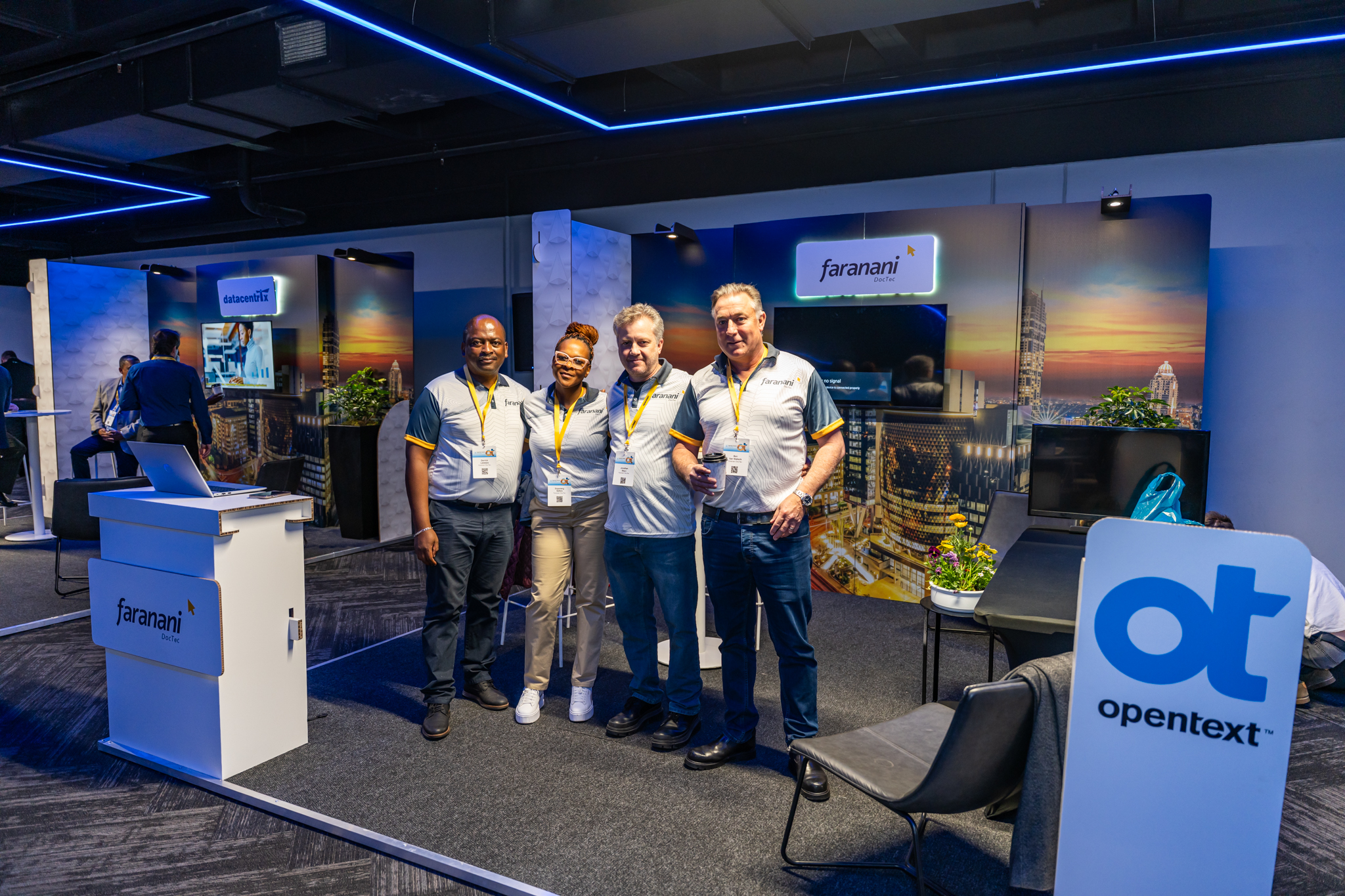 Four Faranani DocTec employees standing shoulder to shoulder in the company booth for OpenText Summit Africa 2025.